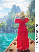Solitude in Paradise - Woman in Red Admires Cheow Lan Lake Emerald Waters Amidst Khao Sok Limestone Cliffs from a Traditional Longtail Boat. Стоковое фото, фотограф Владимир Разгуляев / Фотобанк Лори