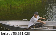 A young man is paddling his boat and trying to dock it at the riverbank. Стоковое видео, видеограф Strunov David / Фотобанк Лори