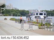 Белый теплоход причаливает, припаркованный, ждет туристов и отдыхающих на прогулку поездку по реке с экскурсией. Озеленение набережной причала Москва реки в парке музее заповеднике Коломенское.Огромные полусферы вазоны для уличных цветов. Редакционное фото, фотограф Светлана Русских / Фотобанк Лори