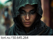 Woman warrior wearing dark clothes and hood starring with painted face. Стоковое AI-изображение, AI-художник Иван Рябоконь / Фотобанк Лори