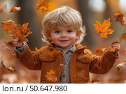 Little boy having fun during stroll in the forest at sunny autumn day. Child playing maple leaves. Baby tossing the leaves up. Active family time on nature. Hiking with little kids. Dry leaves rustle. Стоковое AI-изображение, AI-художник Ирина Михайличенко / Фотобанк Лори