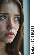 A close-up portrait of a sad, pensive young woman with freckles and blue eyes, looking thoughtfully out a window on a rainy day. Стоковое AI-видео, аниматор Sergey Grishin / Фотобанк Лори