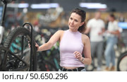 Portrait of positive woman standing in bicycle store and choosing new comfortable bike. Стоковое видео, видеограф Яков Филимонов / Фотобанк Лори