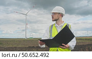 A safety inspector checks the wind turbine for any potential hazards on a rainy day prior to a thunderstorm. Стоковое видео, видеограф Strunov David / Фотобанк Лори