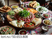Traditional moroccan tagine meal with sides on table. Стоковое AI-изображение, AI-художник Иван Рябоконь / Фотобанк Лори