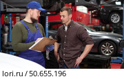 Mechanic guy signs agreement with young man client. Стоковое видео, видеограф Яков Филимонов / Фотобанк Лори