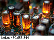 Electrolytic capacitors glowing on circuit board close up. Стоковое AI-изображение, AI-художник Иван Рябоконь / Фотобанк Лори