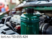 Green coolant expansion tank in the car engine compartment. Стоковое AI-изображение, AI-художник Иван Рябоконь / Фотобанк Лори