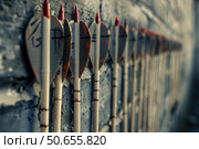 Wooden arrows with red tips hanging on a concrete wall. Стоковое AI-изображение, AI-художник Иван Рябоконь / Фотобанк Лори