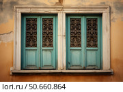Two old turquoise windows with decorative grilles on a damaged orange wall. Стоковое AI-изображение, AI-художник Иван Рябоконь / Фотобанк Лори