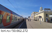 Пассажирский поезд стоит на перроне у старинного здания железнодорожного вокзала. Люди ходят по перрону вдоль вагонов.  Россия, Ярославль, 22 мая 2025. Редакционное видео, видеограф Ирина / Фотобанк Лори