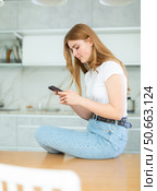 sad girl in white t-shirt and jeans sits on kitchen table and communicates on social network. Стоковое фото, фотограф Яков Филимонов / Фотобанк Лори