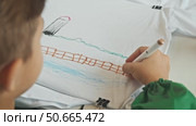 The youngster showcases his artistic abilities by designing a T-shirt using a marker and applying his own artwork. Стоковое видео, видеограф Strunov David / Фотобанк Лори