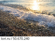 Gentle waves lapping against a pebbled shore at sunset, creating a serene coastal atmosphere. Стоковое фото, фотограф Наталья Семкина / Фотобанк Лори