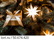 Holiday toys and a golden gift box on a Christmas tree in Moscow. The concept of buying and giving gifts. New Year's card 2026. Стоковое фото, фотограф Photojuli / Фотобанк Лори
