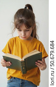 A Joyful Young Girl in a Yellow Shirt Engages With a Green Book, Displaying Her Love for Reading in a Bright, Inviting Setting. Стоковое AI-видео, аниматор Sergey Grishin / Фотобанк Лори