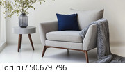 Interior of living room. Gray armchair, green pillow, coffee table and beige wall. Velour Chair against light wall, wooden floor, parquet. Home improvement. Beautiful luxurious modern room settings. Стоковое AI-изображение, AI-художник Марина Демидюк / Фотобанк Лори