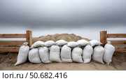 Sandbags line a protective barrier in a construction area during daytime. Стоковое AI-изображение, AI-художник Katsiaryna Repich / Фотобанк Лори