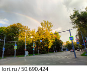 Перекресток на фоне радуги и зеленых деревьев в городе. Москва, Башиловская улица после дождя (2024 год). Редакционное фото, фотограф Ирина Терентьева / Фотобанк Лори