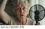 Stressed old woman waving fan suffer from overheating at home. Стоковое AI-видео, аниматор Sergey Grishin / Фотобанк Лори