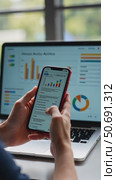 Woman hold smartphone use pc at workplace. Project stats financial data sales charts on laptop and cellphone screen, close up view over shoulder. Report preparation, synchronizatio. Стоковое AI-видео, аниматор Sergey Grishin / Фотобанк Лори