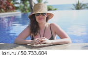 Beautiful young girl in swimsuit and straw hat relaxing by the swimming pool during summer holiday. Copy space. Summer and vacation, sunbathing wellness Lifestyle concept. High quality footage. Стоковое видео, видеограф Ирина Михайличенко / Фотобанк Лори
