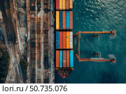 Container ship docking at industrial port with railroad tracks, aerial view. Стоковое AI-изображение, AI-художник Иван Рябоконь / Фотобанк Лори