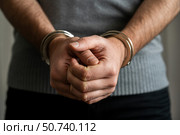 Hands of a person in handcuffs, showing tension and restraint in a neutral setting. Стоковое AI-изображение, AI-художник Гайфуллина Дина / Фотобанк Лори