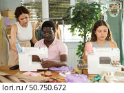 Experienced seamstress mentoring fashion students in garment construction class. Стоковое фото, фотограф Яков Филимонов / Фотобанк Лори