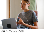 Teen girl school student wear headphones watching online webinar, talking through webcam looking at laptop. Teenager conducting video conference on computer at home, chatting online with friends. 4K. Стоковое фото, фотограф Марина Демидюк / Фотобанк Лори