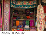 Colorful traditional textiles displayed on shelves and hanging in a textile shop. Стоковое AI-изображение, AI-художник Иван Рябоконь / Фотобанк Лори