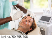 African male specialist uses ultrasonic import nozzle to care man client face skin. Стоковое фото, фотограф Яков Филимонов / Фотобанк Лори