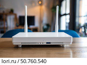 Modern wireless router with dual antennas on wooden table. Стоковое AI-изображение, AI-художник Иван Рябоконь / Фотобанк Лори