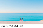 Oceanfront Contemplation: Two Women Seated by Turquoise Sea. Стоковое AI-изображение, AI-художник Данила Большаков / Фотобанк Лори