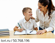 Мальчик делает уроки за столом, а мама ему помогает. The boy does his homework at the table, and his mother helps him. Стоковое AI-изображение, AI-художник Смирнова Светлана / Фотобанк Лори