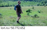 Exploring Nature a Hiker with backpack Strolling Through a Beautiful Field Beneath Vast Blue Sky. Tourist man traverses a scenic field, clear blue sky. Adventure and exploration concept. One person. Стоковое видео, видеограф Марина Демидюк / Фотобанк Лори