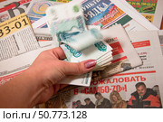 Рука с российскими рублями на фоне газет. Стоковое фото, фотограф Мария Деркунская / Фотобанк Лори