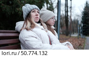 Mother and daughter in the city. Relaxed woman and daughter going to autumn street, sitting on a park bench. Teen girl student wear warm clothes winter jacket. Teenager out for walk with mom. 4K. Стоковое видео, видеограф Марина Демидюк / Фотобанк Лори