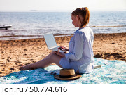 Working on a Laptop While Enjoying the Tranquility of a Sandy Beach by the Ocean Under a Bright Sun. Стоковое фото, фотограф Aleksandr Golubev / Фотобанк Лори
