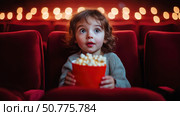 Adorable child with wide eyes holding popcorn in red theater seat, captivated by movie screen, surrounded by cinematic lights, evoking wonder and childhood joy. Стоковое AI-изображение, AI-художник Катерина Бондарец / Фотобанк Лори