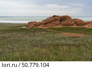 Fancy stones on the slopes of Bolshoe Bogdo Mountain and the salt lake Baskunchak in the distance on a summer day, Bogdinsko-Baskunchak Nature Reserve, Akhtubinsky district, Astrakhan region, Russia. Стоковое фото, фотограф Ula Ulachka / Фотобанк Лори