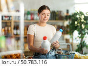 Girl hold packages bottles and choose consider milk in store. Стоковое фото, фотограф Яков Филимонов / Фотобанк Лори