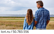 Father and daughter looking at solar panels. Solar farm and sunlight at sunset. Solar energy for green energy. Sustainable renewable energy. Photovoltaic power plant or solar park. Energy sustainability. Стоковое AI-изображение, AI-художник ALLA YURTAYEVA / Фотобанк Лори