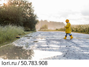 A boy in yellow rubber boots and a raincoat runs through puddles, having fun and playing with a remote-controlled car after it rains. Summer and autumn holidays. A happy childhood. Стоковое фото, фотограф Photojuli / Фотобанк Лори
