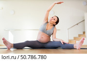 Pregnant woman is engaged in yoga. Revolved seated side angle pose or Parivrtta Upavistha Konasana. Стоковое фото, фотограф Татьяна Яцевич / Фотобанк Лори