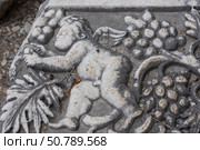 Bas-relief on the surface of a stone block in the ancient city of Perge in Turkey. An image of an angel and grapes on a stone surface. Grape leaves and berries next to an angel on a stone. Стоковое фото, фотограф Эдуард Белкин / Фотобанк Лори