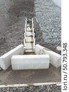 Concrete drainage channel with embedded plastic pipe for stormwater management, set against gravel and gabion-covered slope. Стоковое фото, фотограф Софья Соломонова / Фотобанк Лори