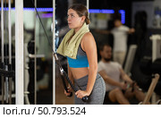Girl in gym performs exercises for arm muscles using cable machine and pull weighted rope. Стоковое фото, фотограф Яков Филимонов / Фотобанк Лори