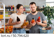 Spouses hold packages bottles and choose consider juice in store. Стоковое фото, фотограф Яков Филимонов / Фотобанк Лори