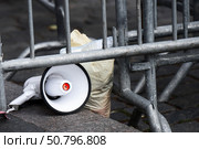 Portable loudspeaker discarded near trash bags and temporary barriers - concept of abandoned propaganda or protest cleanup. Стоковое фото, фотограф Татьяна Степанищева / Фотобанк Лори